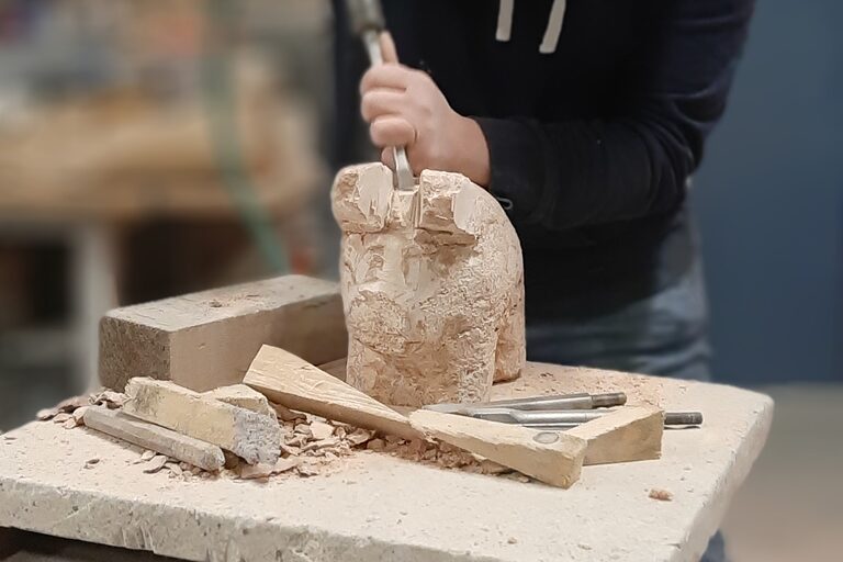 "Bearbeiten einer Skulptur: mit Eisen und Presslufthammer an Glücksschwein aus Marmor."