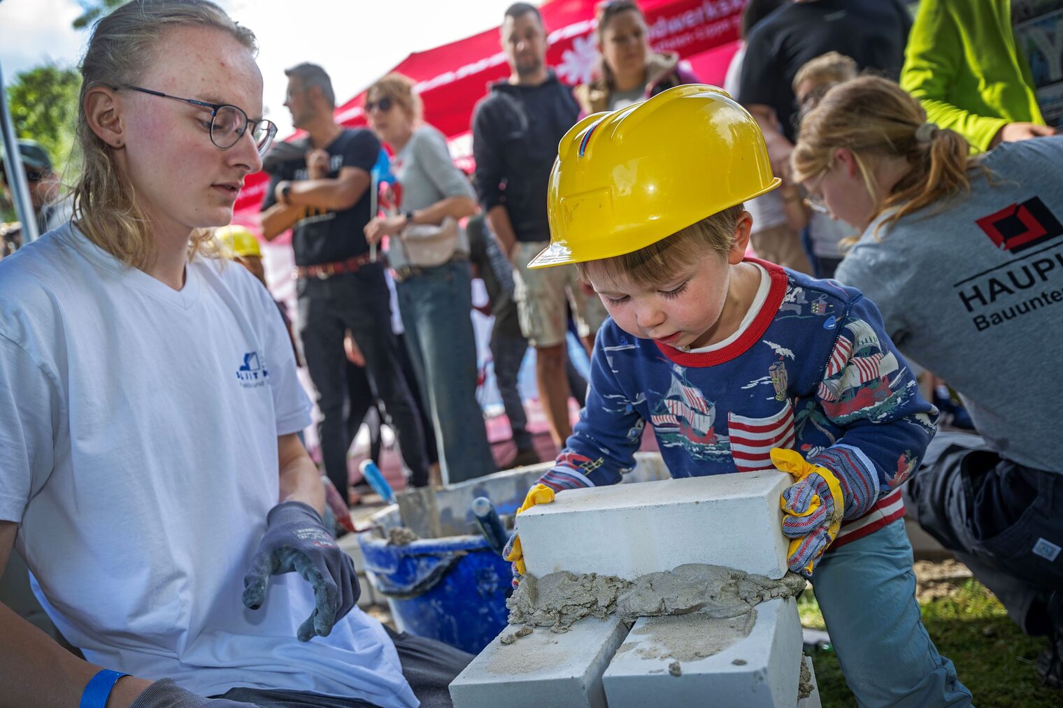 Mats (r.) baut unter Anleitung von Erik Stegmann (Splietker Bau GmbH & Co. KG) eine kleine Mauer. 