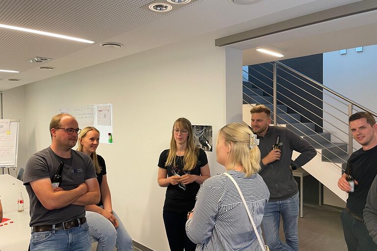 Junge Leute stehen sich in Seminarraum gegenüber und unterhalten sich 