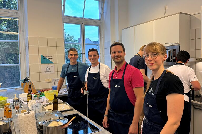 4 Junge Leute lachen während sie in der Küche kochen in die Kamera