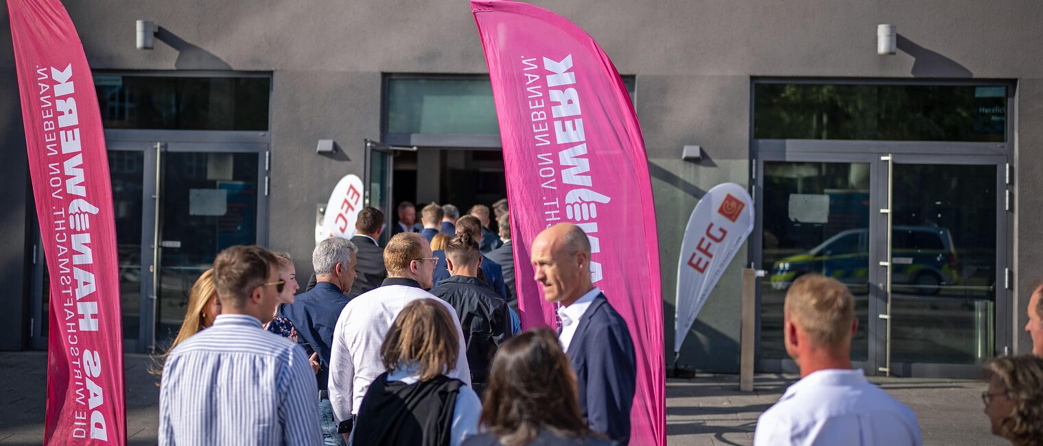 Die Gäste der Meisterfeier stehen Schlange vor der Stadthalle Bielefeld. Oben hängt ein Banner mit "meisterhaft". 