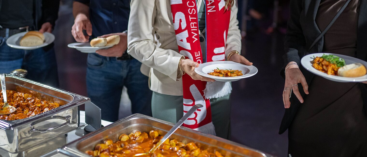 Gäste der Meisterfeier bedienen sich am Buffet mit Pasta und Currywurst. 