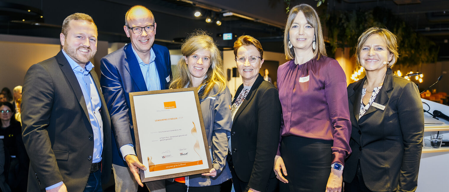 Glückliche Preisträger*innen halten die Urkunde in die Kamera.