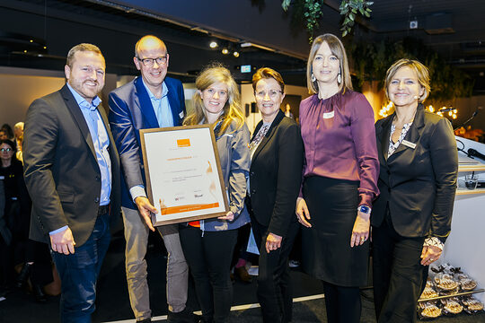 Glückliche Preisträger*innen halten die Urkunde in die Kamera.