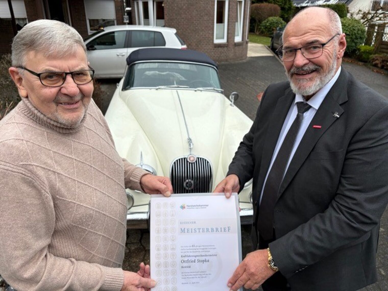 Kammerpräsident Peter Eul und Jubilar Ottfried Stopka mit dem seltenen Eisernen Meisterbrief neben dem Oldtimer Jaguar XK 150. 