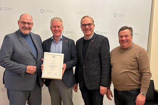 Die Handwerkskammer OWL übergibt Holger Schwannecke die goldene Ehrennadel.