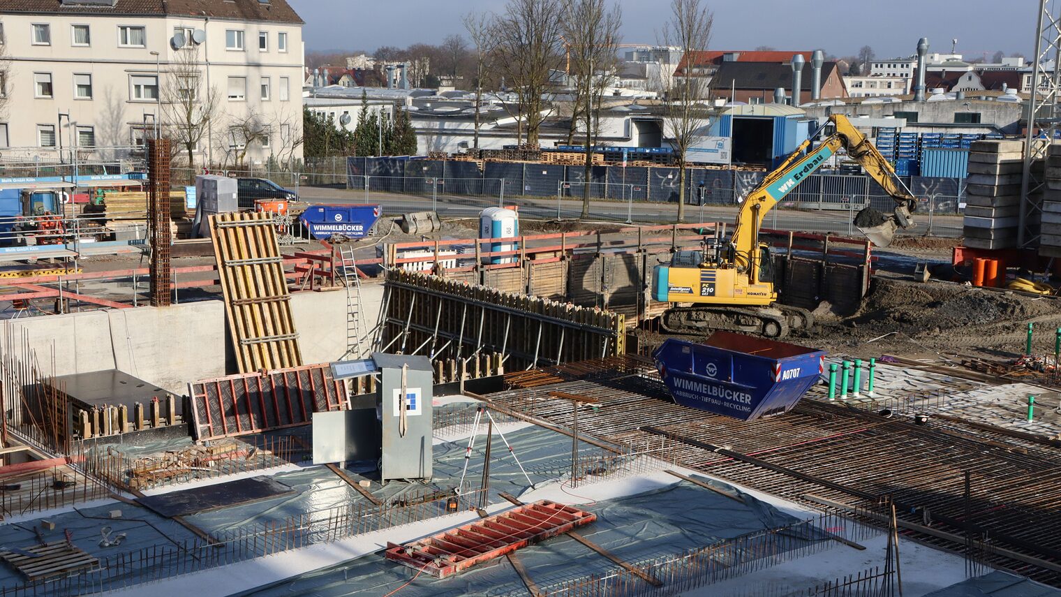 Der Neubau am Campus Handwerk schreitet voran. Zu sehen ist ein Bagger, der Erde schaufelt, und die fast fertige Bodenplatte.