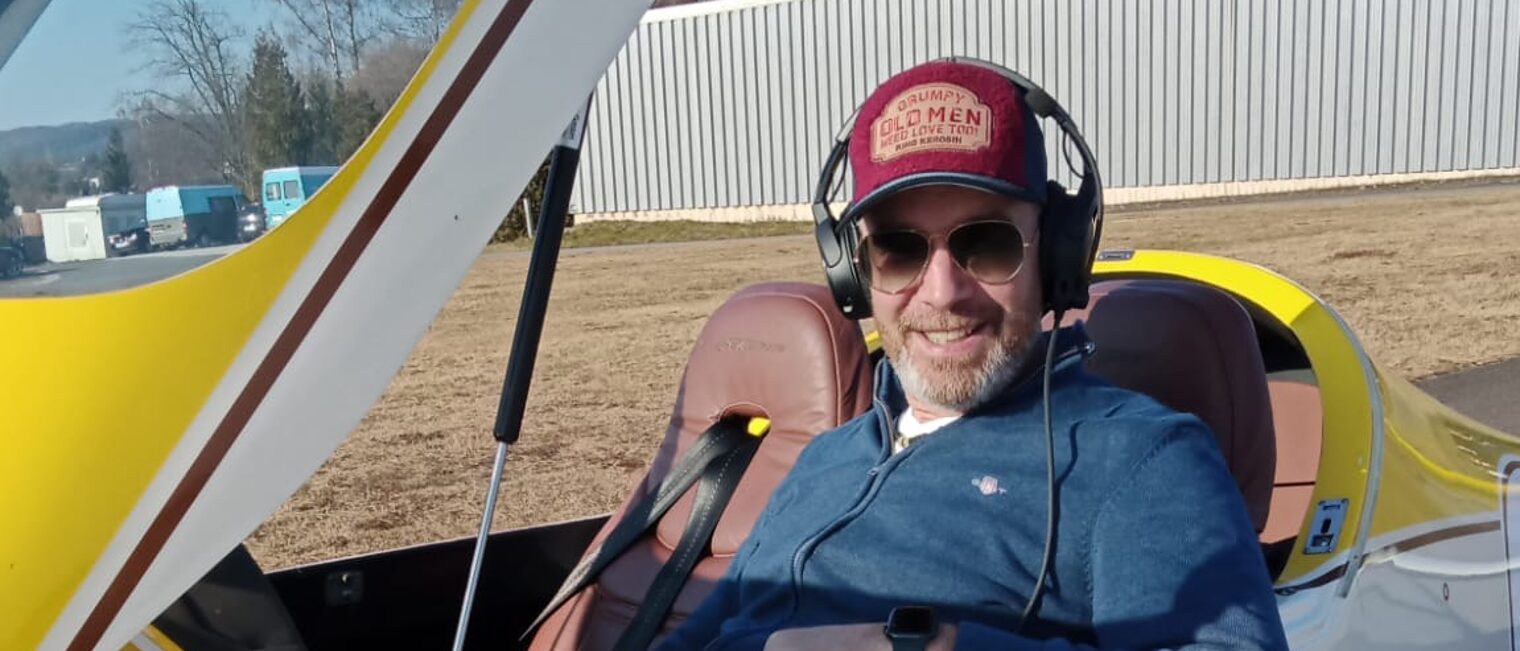 Markus Hombrink sitzt in einem gelb-weißen Ultraleichtflugzeug, bereit zum Start.